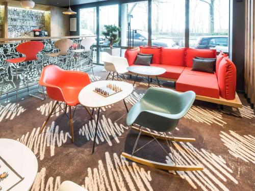 鲁昂ibis Rouen Centre Champ de Mars的一间设有红色沙发、椅子和桌子的客房