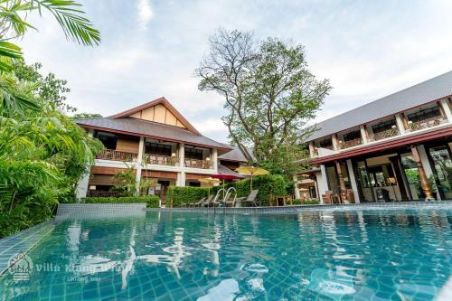 清迈Villa Klang Wiang的一座带游泳池的度假村,位于一座建筑前