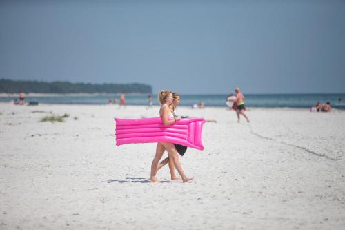 内克瑟Dueodde Hostel的一位女士在海滩上用粉红色的毛巾行走