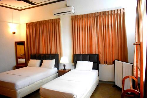 贾夫纳Old Park Villa的配有橙色窗帘的酒店客房的两张床