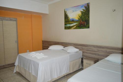 伊塔皮波卡Pousada Ayrumã的一间设有两张床的客房,墙上挂着一幅画