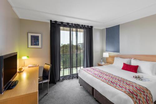 悉尼Nesuto Parramatta的酒店客房配有一张床、一张书桌和一台电视。