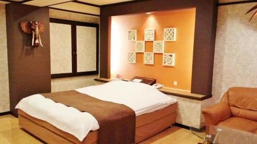 宫崎Ciao-LoveHotel的一间卧室配有一张大床和一把椅子