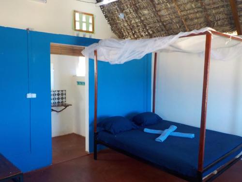 迭戈苏瓦雷斯SANJEELA-PLAGE COCO的一间卧室配有一张带天蓬的蓝色床
