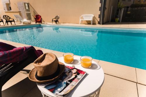 热尔扎克莱蒙费朗 - 格尔扎特花园和城市公寓的池畔桌子上一顶帽子和两杯橙汁