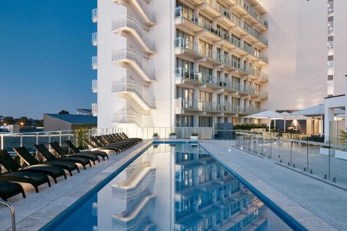 阿德莱德艺术系列酒店 - 沃森的酒店游泳池设有椅子,酒店大楼