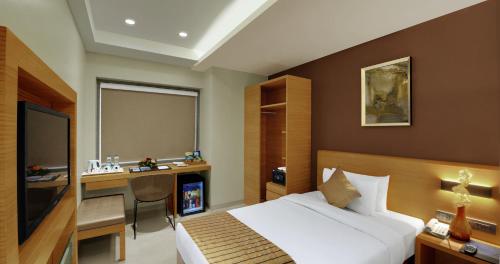 巴罗达Hotel Suba Elite Vadodara的配有一张床和一张书桌的酒店客房