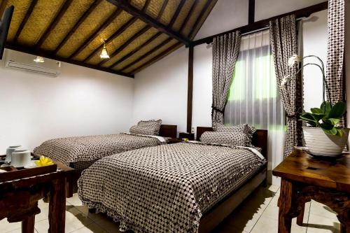 婆罗浮屠The Omah Borobudur的一间卧室设有两张床、一张桌子和一个窗口