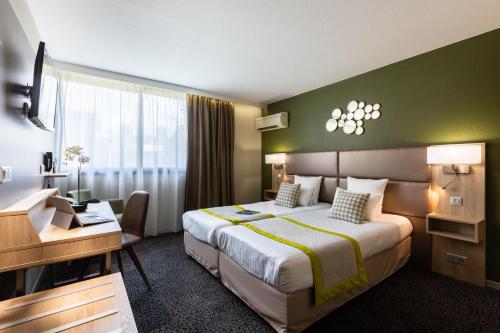 梅里尼亚克波尔多机场基里雅德普雷斯蒂奇酒店的配有一张床和一张书桌的酒店客房