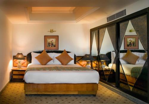新德里新德里苏尔亚酒店的一间卧室配有一张床、两盏灯和两张床