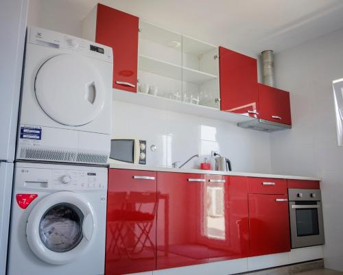 马亚Maiahouse的一间带红色橱柜和洗衣机的厨房