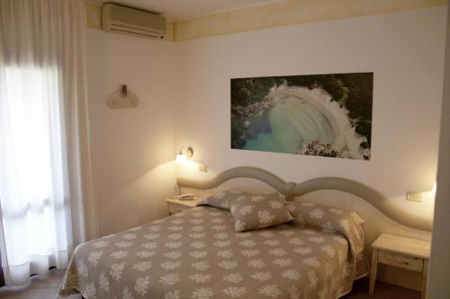 帕劳波尔图曼努公寓酒店的卧室配有一张床,墙上挂有绘画作品