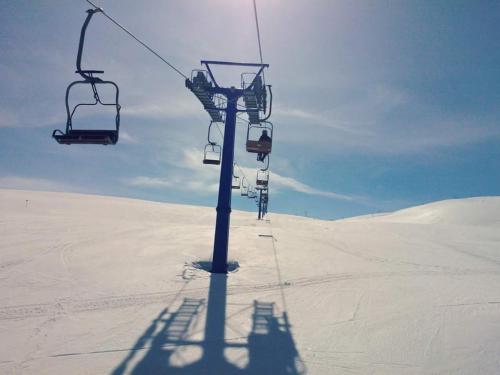 Popova ShapkaVilla Winterfell Popova Shapka的雪覆盖的田野中间的滑雪缆车