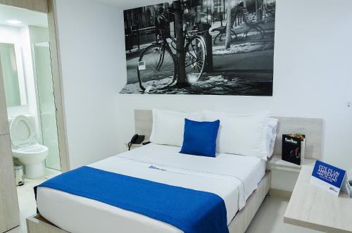 麦德林Hotel Laureles Plaza的一间卧室配有一张带蓝色枕头的床