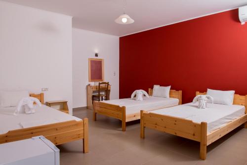 马塔拉Paradise Matala Hotel的一间设有三张床和红色墙壁的房间