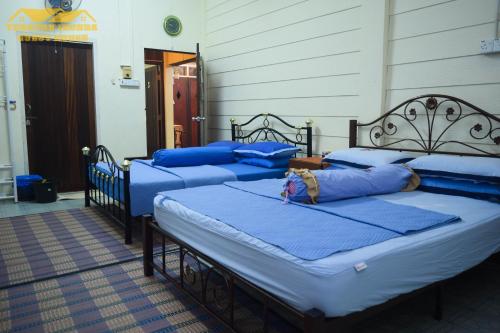 哥打巴鲁Teratak Ibunda Guest house的客房内的三张床和蓝色枕头