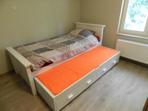 赫纲兰德Fleur d’ Amour的一间小卧室,配有一张带橙色床垫的床
