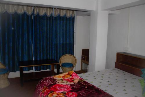 大吉岭Riva homestay family room的一间卧室配有床和蓝色窗帘的窗户
