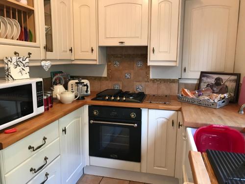 绍斯韦尔Southwell的厨房配有白色橱柜和炉灶烤箱。