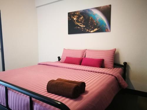 清迈Duangdren Apartment的一间卧室配有粉红色的床和棕色枕头