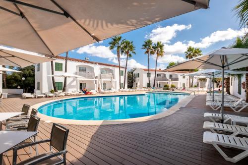 休达德亚Apartaments Cales de Ponent的度假村的游泳池,配有椅子和遮阳伞