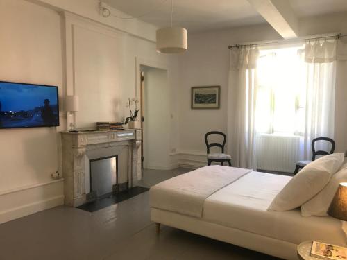 圣加尔米耶Maison Ladeveze的一间白色卧室,配有一张床和一个壁炉