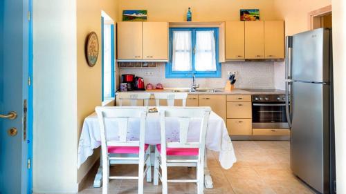 哈尔基岛Amazing House in Halki的厨房配有桌椅和冰箱。