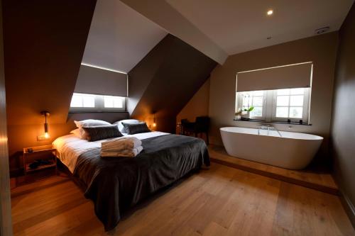 哈瑟尔特Maison Stout的一间卧室设有一张大床和一个浴缸