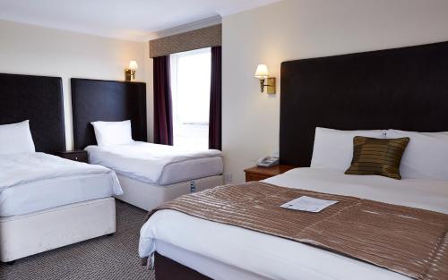 胡克Raven Hotel by Greene King Inns的酒店客房设有两张床和窗户。