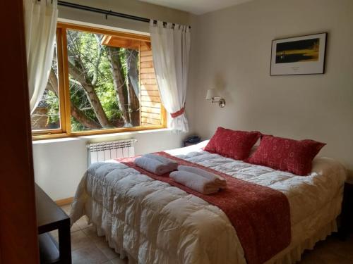 圣马丁德洛斯阿雅德阿尔奎勒图里斯提科公寓的一间卧室配有一张带红色枕头的床和一扇窗户