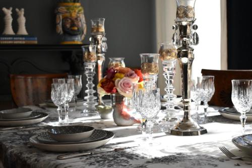 皮亚韦河畔圣多纳Palazzina Mori - Luxury B&B的桌子上放着玻璃杯和盘子,花朵