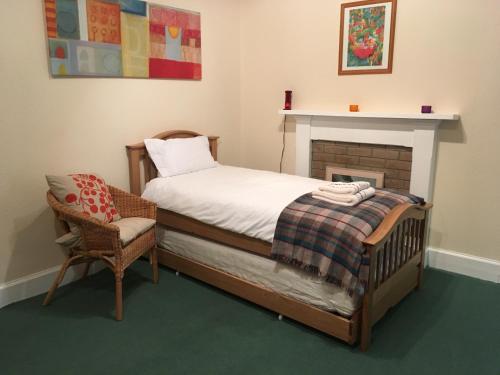 牛顿莫尔Netherwood House的一间卧室配有一张床、一把椅子和一个壁炉