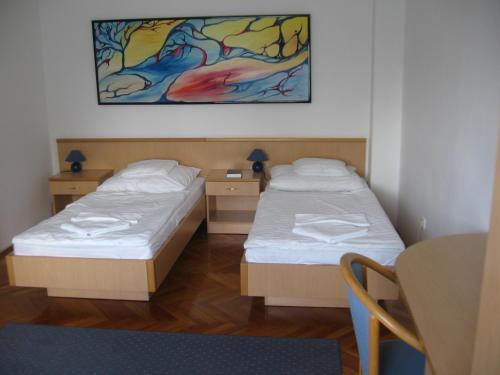 Gönyů莱尔商务酒店的一张桌子和一幅画的房间里,有两张床