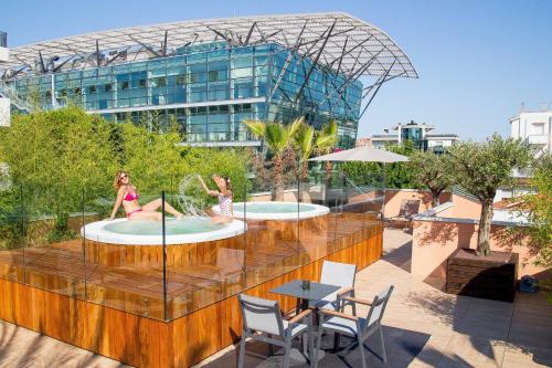 里乔内Metropol Ceccarini Suite - Luxury apartments的两个女孩在建筑物屋顶的两个游泳池玩耍