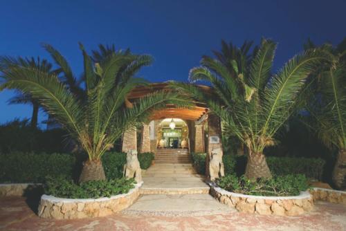 兰佩杜萨Cupola Bianca Resort的两棵棕榈树和走道的房子