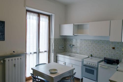 亚历山德里亚Luminoso bilocale的厨房配有白色家电、桌子和窗户