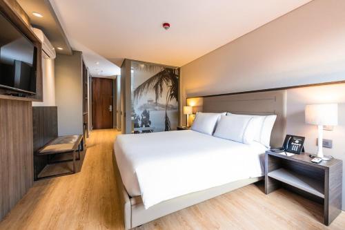 波哥大Hotel Habitel Prime的卧室配有一张白色大床和电视。