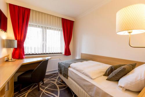 BreidenbachHotel Lang的酒店客房配有一张床、一张书桌和一张书桌。