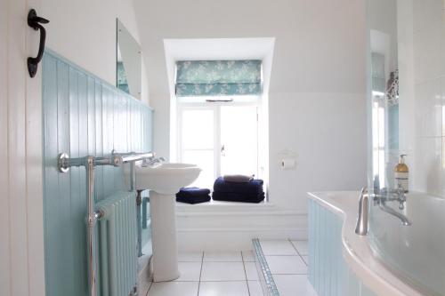 切达Strawberry Cottage的一间带水槽和浴缸的浴室以及窗户。