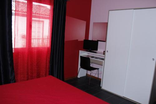 坎普自由鎮Vila Centro的一间卧室设有红色的墙壁和一张带电脑的书桌