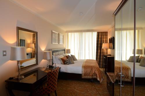 开普敦Taj Luxury Suite的酒店客房带一张床、一张书桌和一面镜子