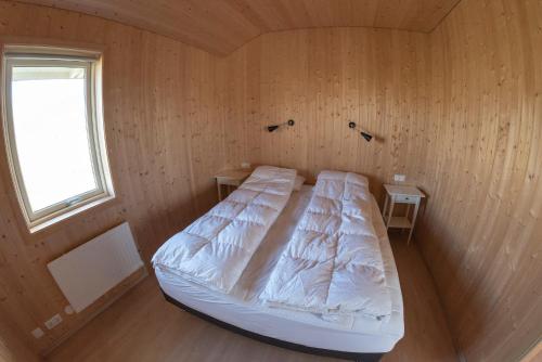 Nesjum磨河度假屋的木制客房的一张床位,设有窗户