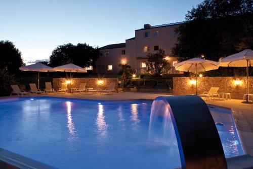 Bouaye爱埃伯特 - 基里亚德酒店的游泳池设有瀑布,晚上提供遮阳伞
