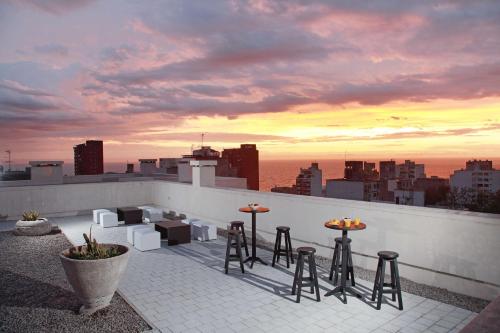 蒙得维的亚Esplendor by Wyndham Montevideo Cervantes的屋顶酒吧设有凳子,享有城市美景