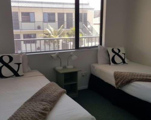 新普利茅斯ASURE Abode On Courtenay Motor Inn的小型客房 - 带2张床和窗户