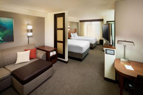达拉斯达拉斯中央公园广场凯悦酒店的酒店客房配有一张床和一张沙发,客房则配有两张床。