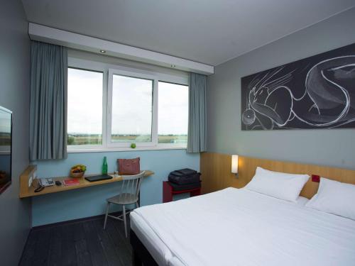 施韦夏特维也纳机场宜必思酒店的酒店客房设有一张床、一张书桌和窗户。