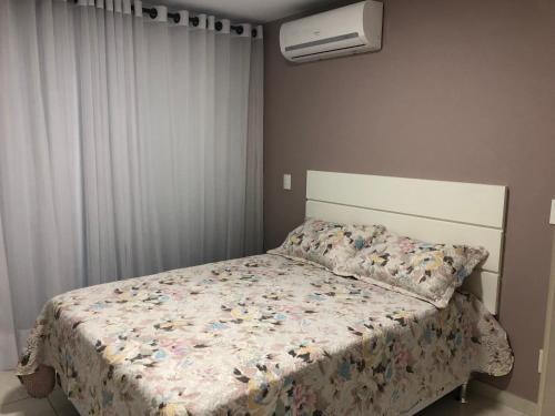 阿拉亚尔-杜卡布Apartamento Aconchegante Em Arraial Do Cabo的一间卧室配有一张带花卉棉被的床
