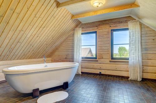 MindūnaiCountry house Stirnamis的木墙客房内的白色浴缸