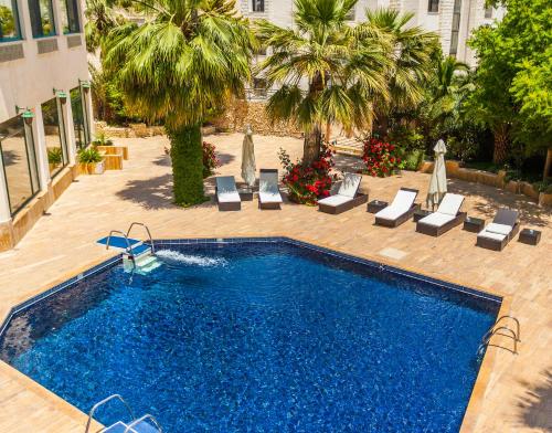 安曼安曼西部酒店的一个带躺椅的游泳池和一间酒店